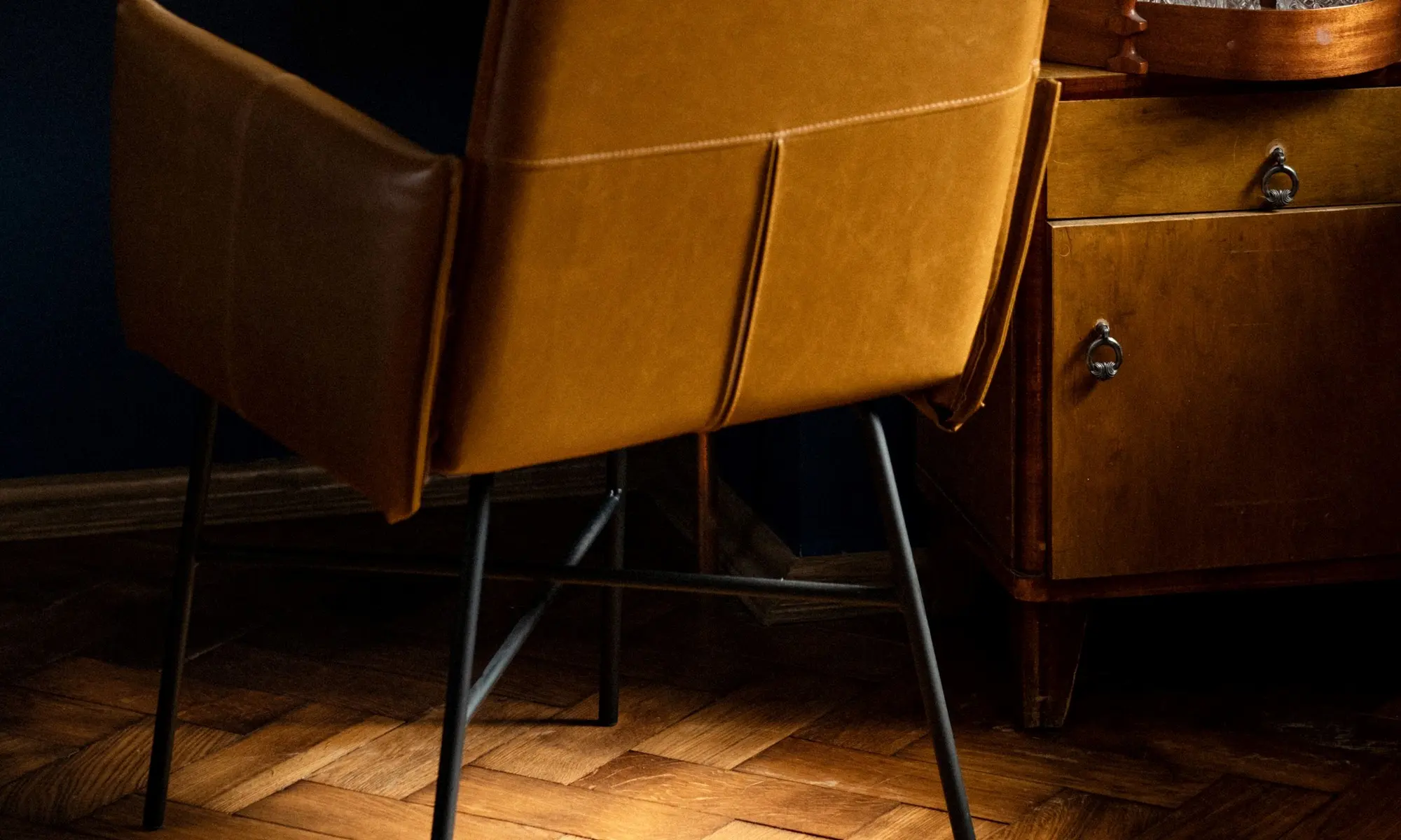 Fauteuil en cuir camel sur un parquet en chevrons, dans une lumière chaude